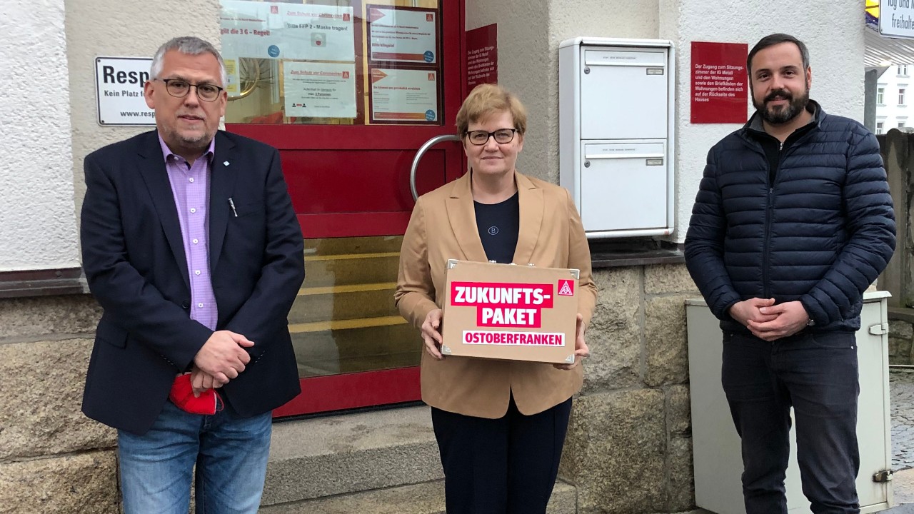 Volker Seidel (links) und Stefan Winnerlein von der IG Metall Ostoberfranken überreichen der Parlamentarische Staatssekretärin Anette Kramme den „Forderungskoffer“ zur Transformation. Foto: IG Metall Ostoberfranken